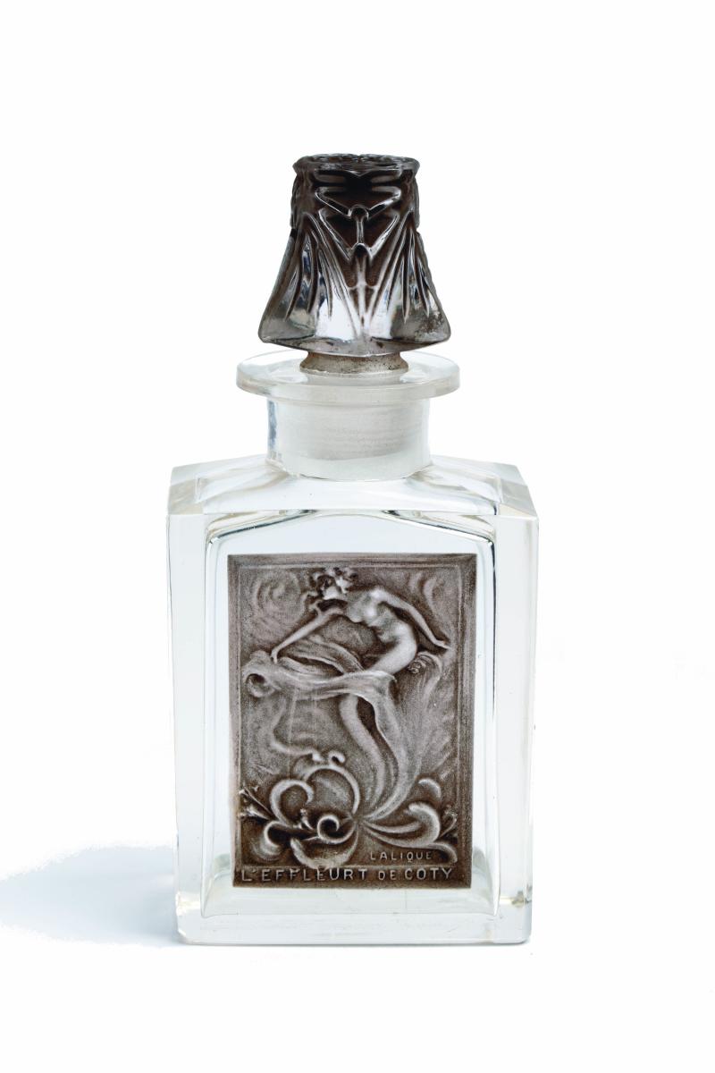 Flacon de parfum en verre  avec une étiquette en verre représentantn une femme dans des effluves de parfum
