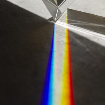 Photo d'un prisme en haut de l'image avec un spectre lumineux qui s'étend vers le bas de l'image