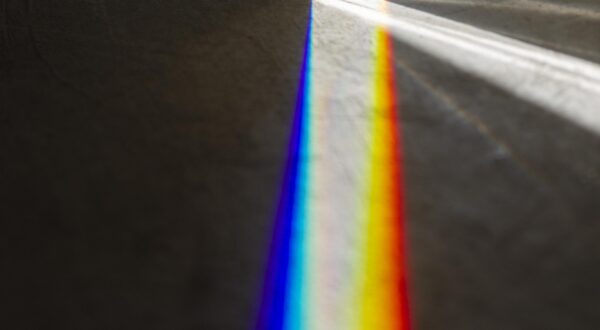 Photo d'un prisme en haut de l'image avec un spectre lumineux qui s'étend vers le bas de l'image